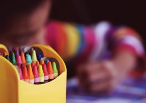 An elementary school kid using crayons