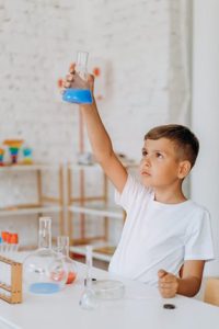 A kid experiments at home, playing with beakers and colored fluids.