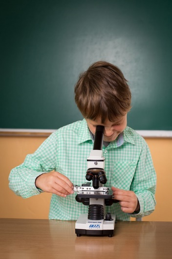 kid watching something through a microscope